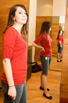 mujer joven parada cerca de un espejo de cuerpo completo
