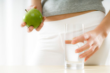 mujer sosteniendo vaso de agua, manzana